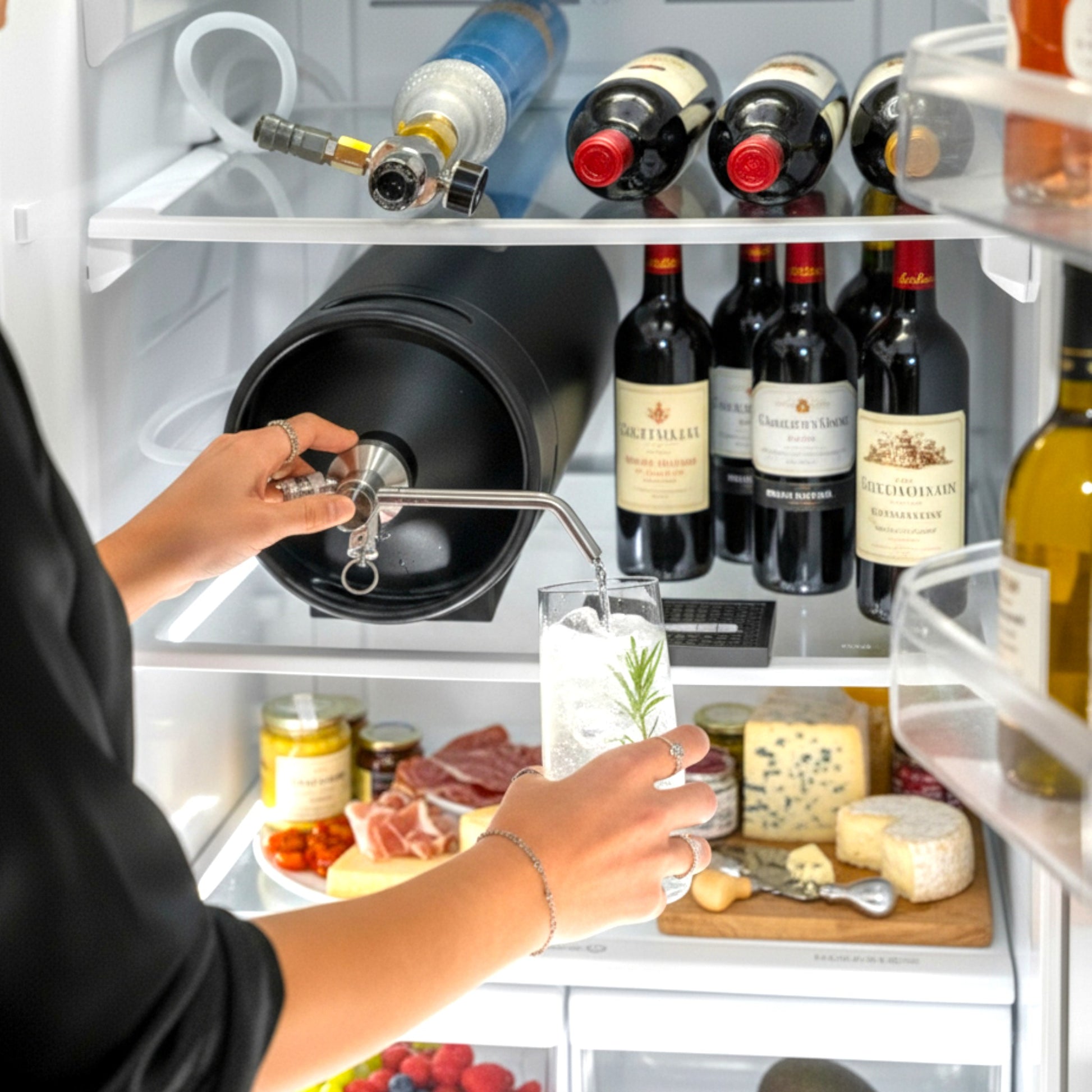 Person pouring a gin and tonic from a lying down ikegger mini keg in an open refrigerator with wine bottles and food items.