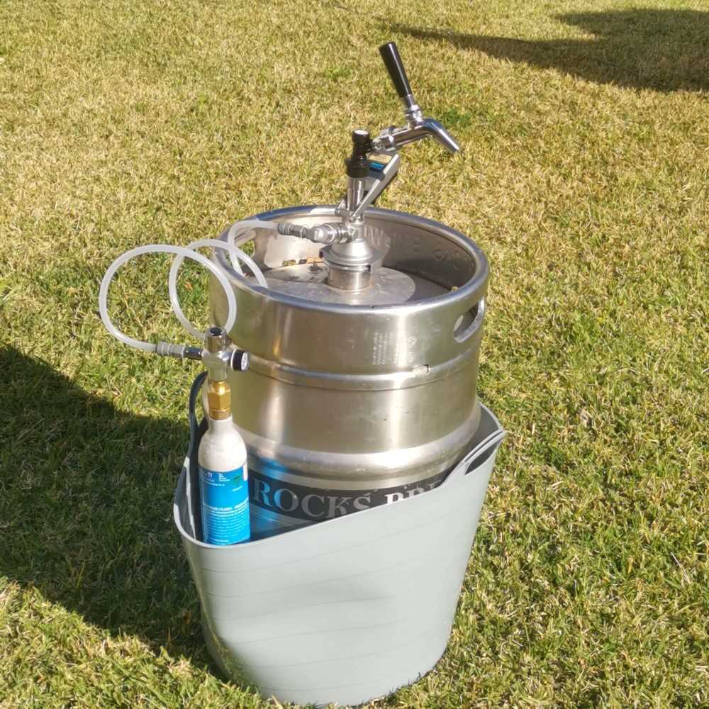 keg tapping kit with the flow control tap directly attached to the keg coupler in a park